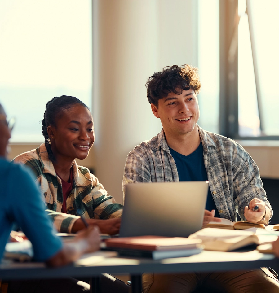 Vrouw en man studeren samen aan een tafel met een laptop en boeken.